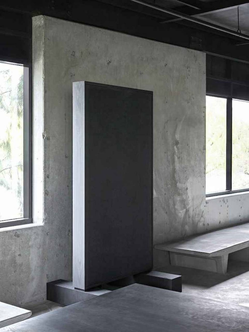 An upright black slab against concrete
