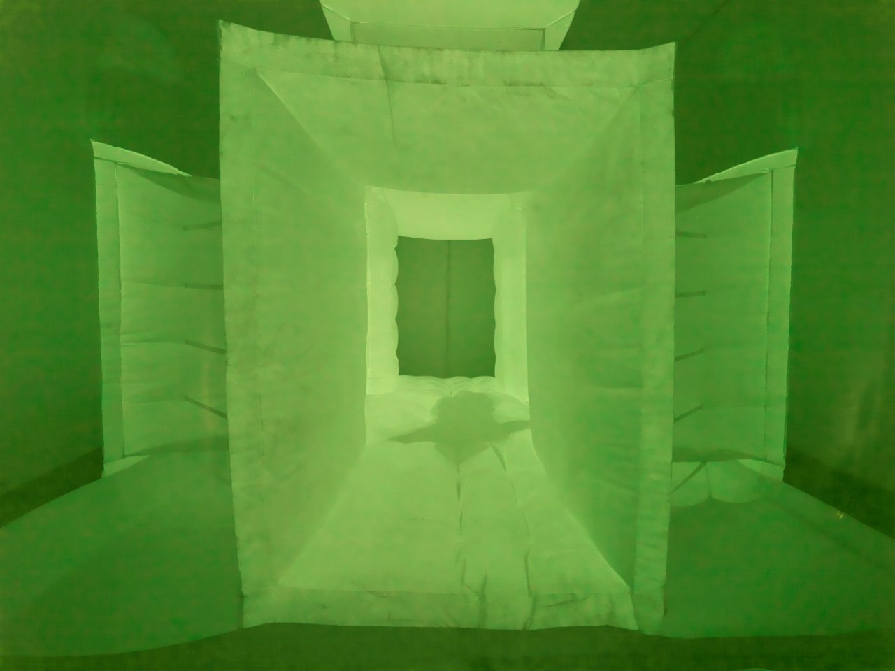 A green fabric with the shadow of a person moving through it