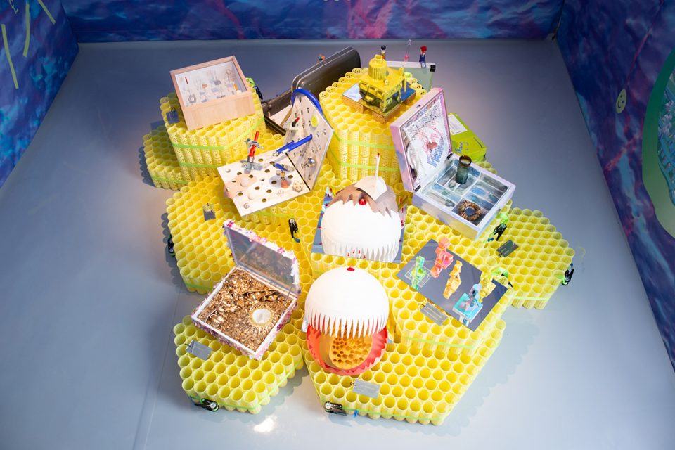 Photo of hexagonal yellow plastic pavilions supporting a variety of cases and small objects