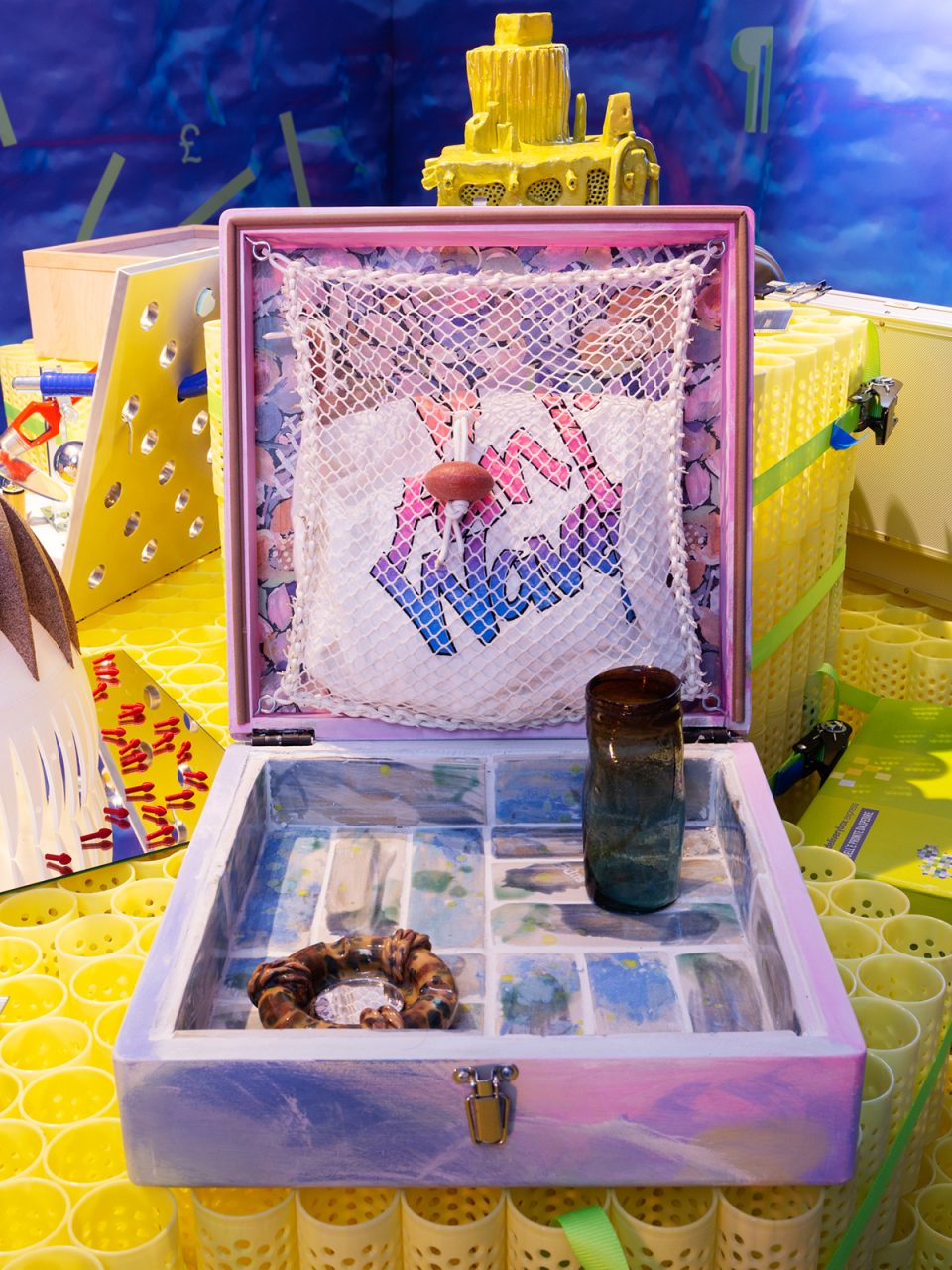 Photo of a lilac valise containing a glass, netting, and a ceramic object