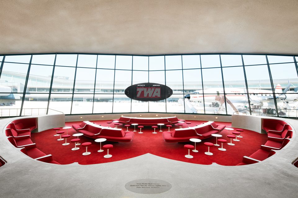 Interior image of red carpeted seating area that overlooks exterior tarmac at JFK