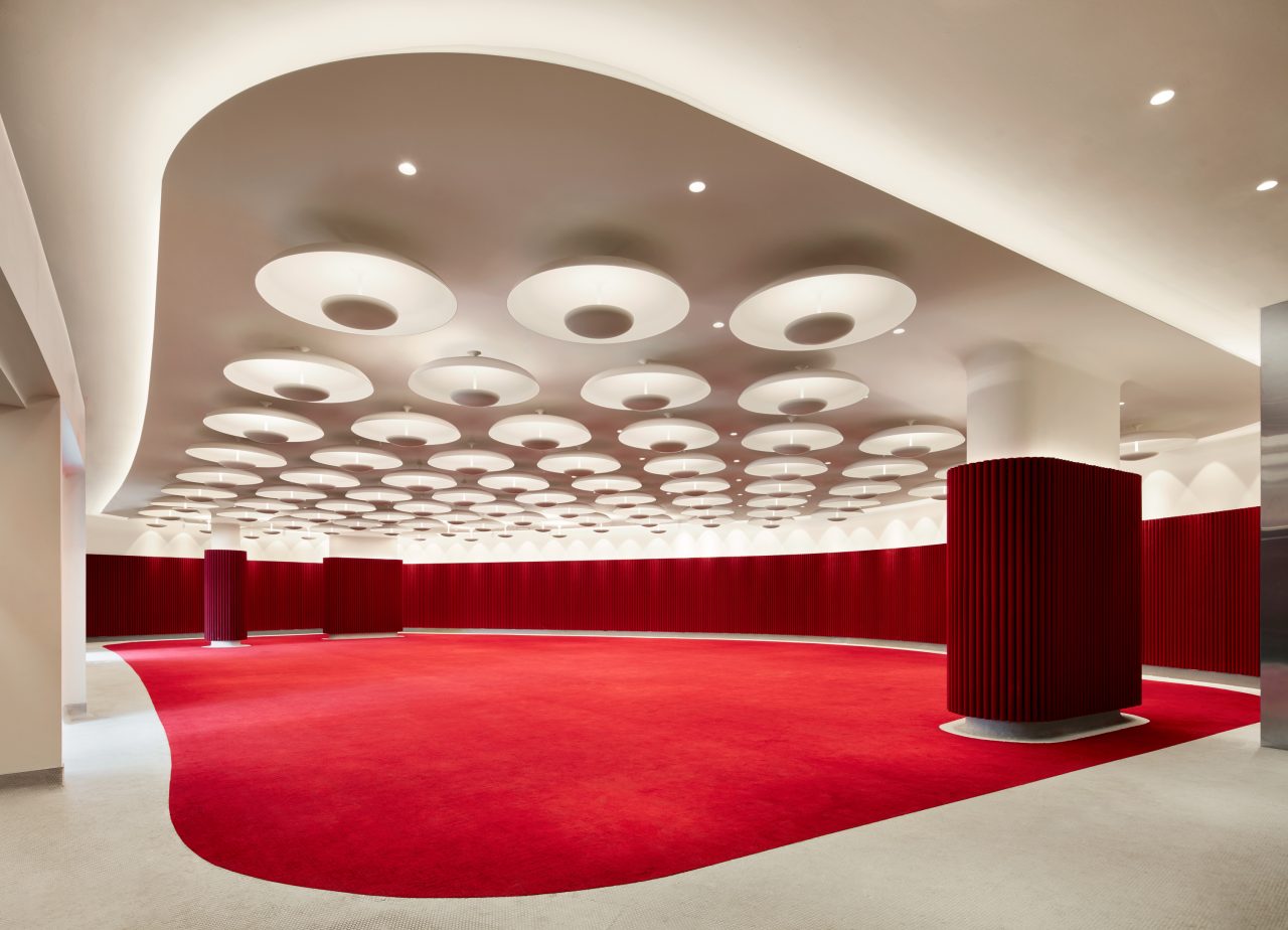 Interior image of ballroom with red carpet and walls and white ceiling with round lights