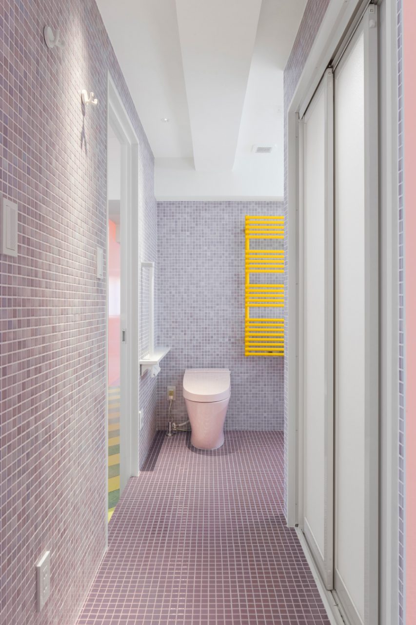 A tile-clad bathroom with a pink toilet