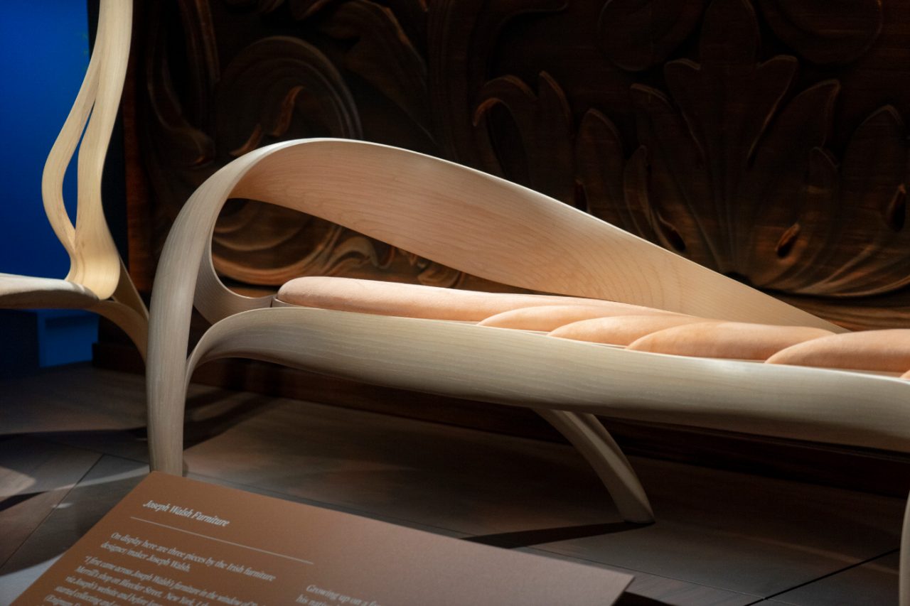 A wooden bench with a curved, flared arm