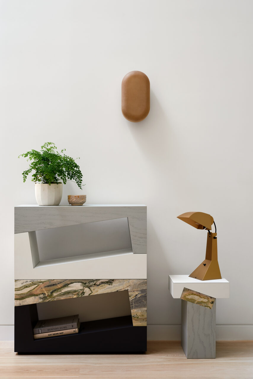 A geometric, mixed-material console table matches a lamp and wall fixture