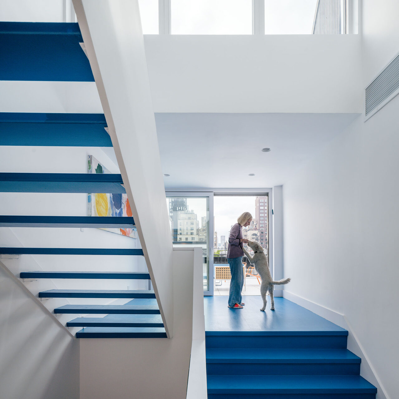 A blue staircase brings a pop of color to the white walls