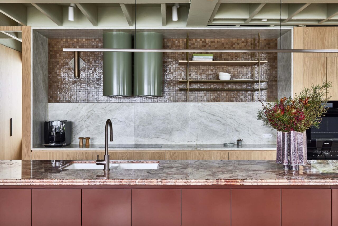 A kitchen defined by marble, warm reds, and green