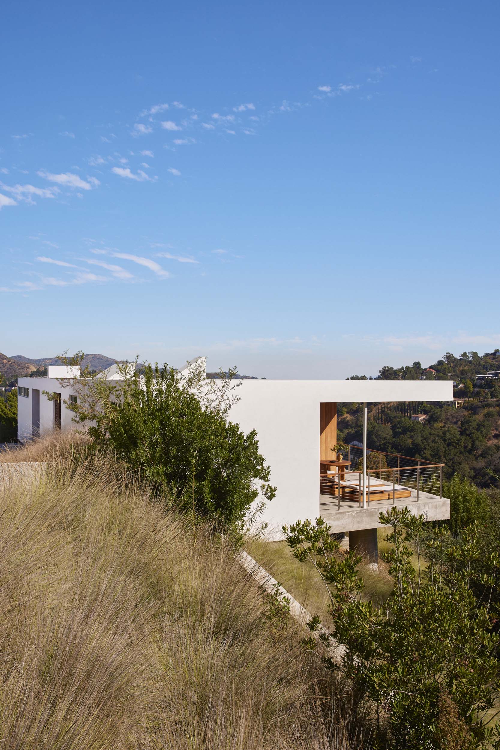 A modern white home with a cantilevered roof hangs over a canyon
