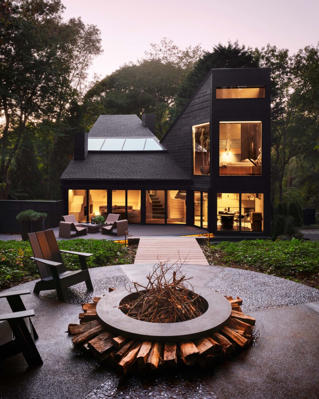 A firepit pathway leads to a modern black home