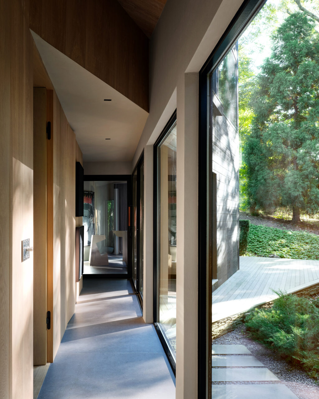 A narrow, linear hallway in a modern home with big windows