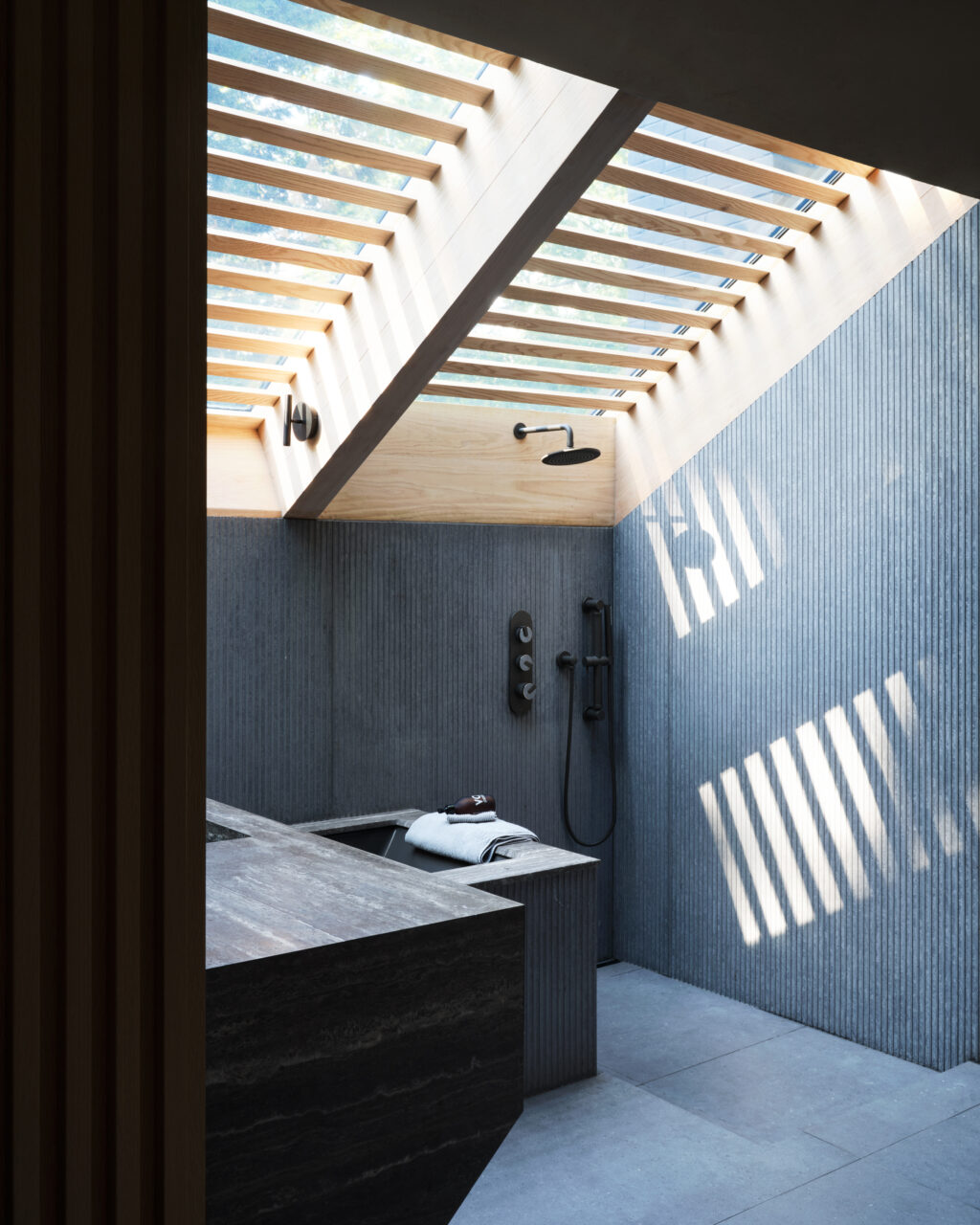 The primary bath’s tub is lit underneath a skylight fitted with wooden slats