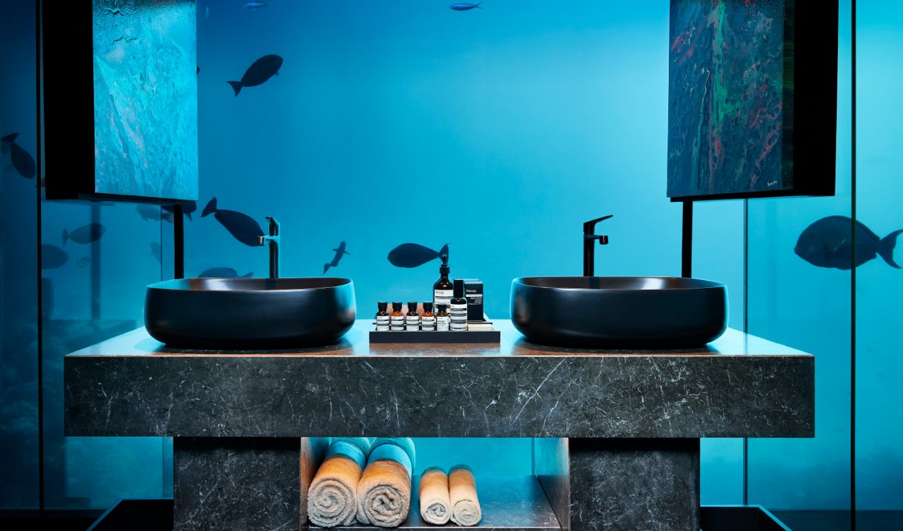 Photo of a sink and soaps against a glass wall