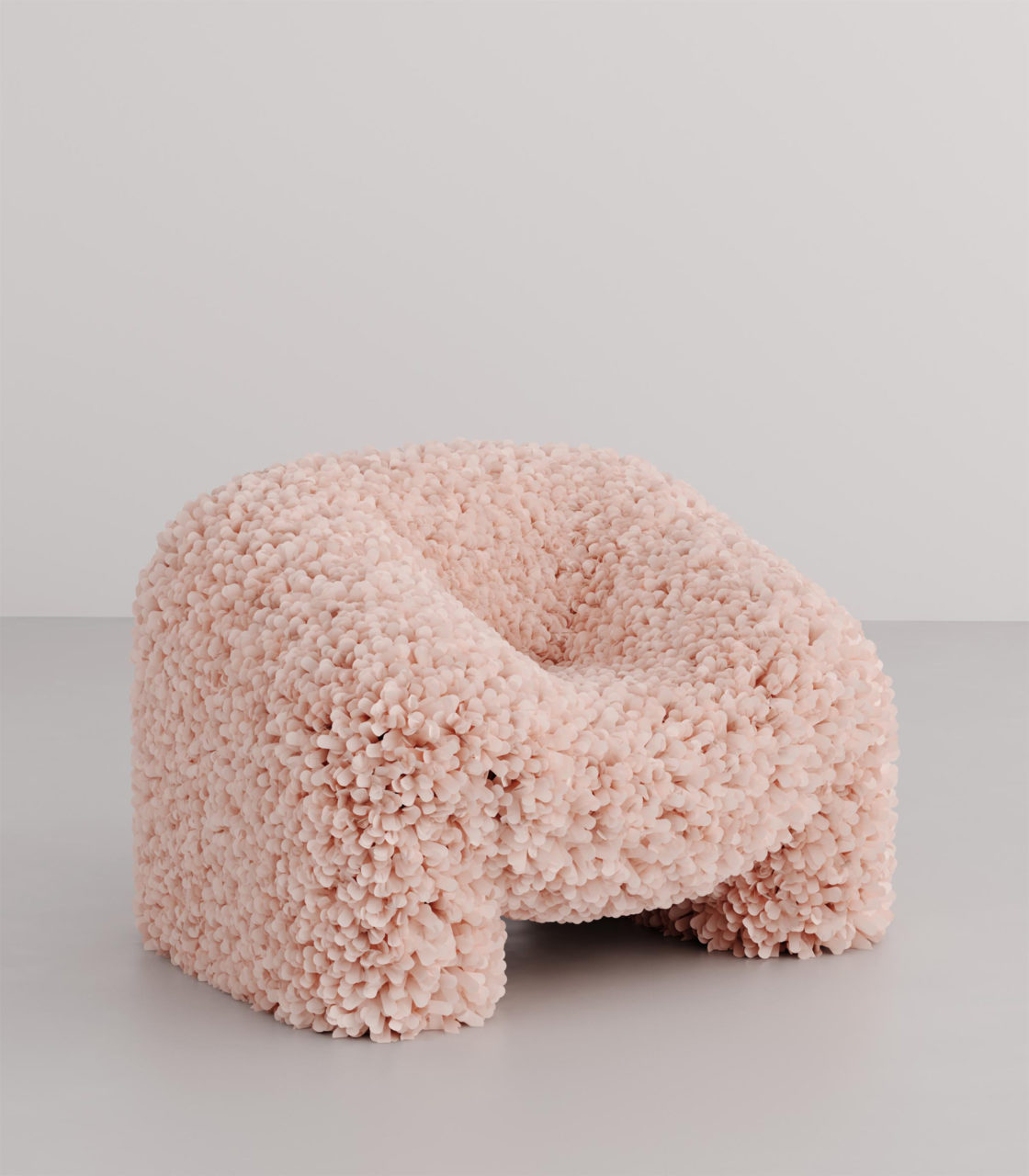 a pink, organic-shaped armchair upholstered in a loose weave textile