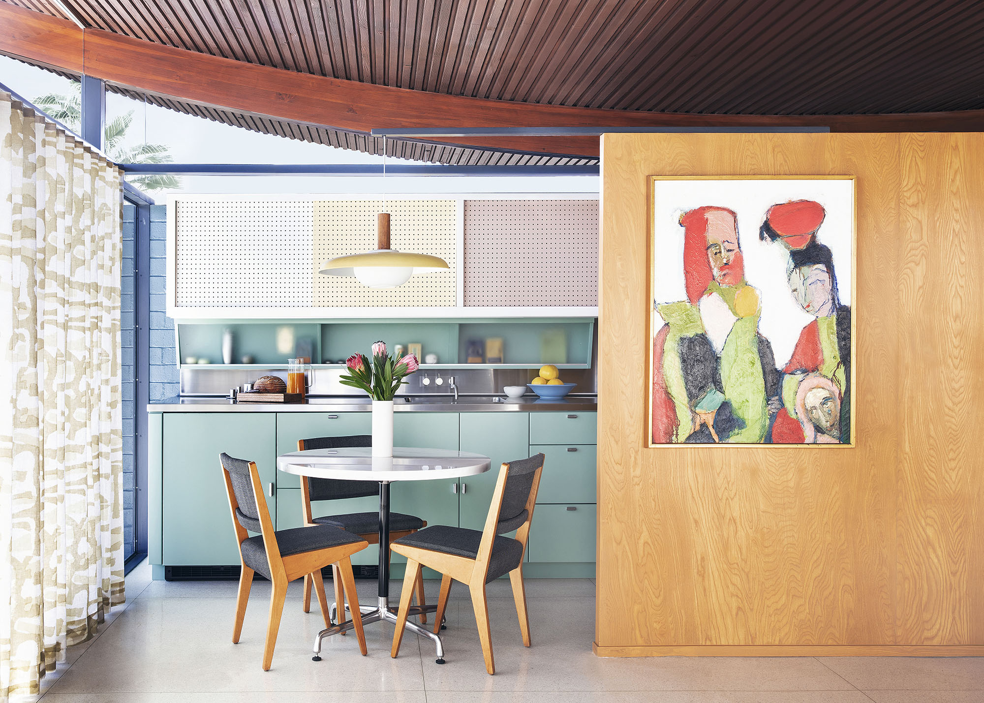 image of an eat-in kitchen with wooden furniture, art work, aqua blue cabinetry, an a curvilinear celing