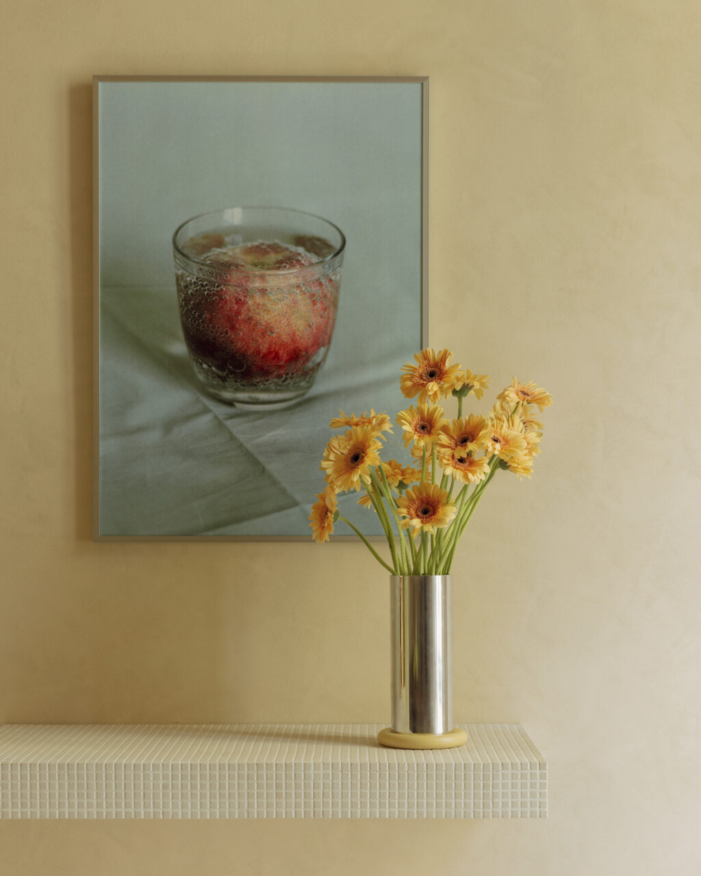 A steel vase with flowers set against a peach-colored wall