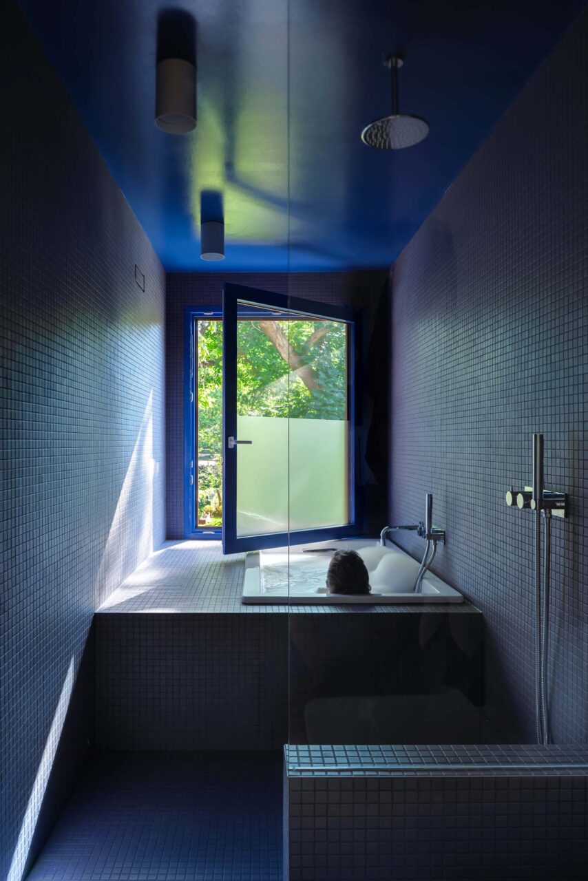 A blue-tiled bathroom with a tub in front