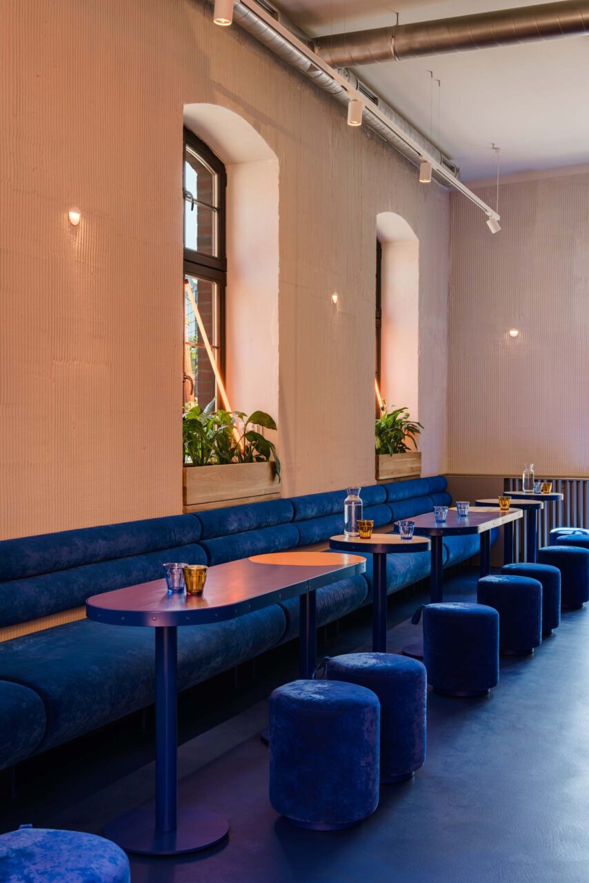 Blue velvet benches and poufs line a bakery wall