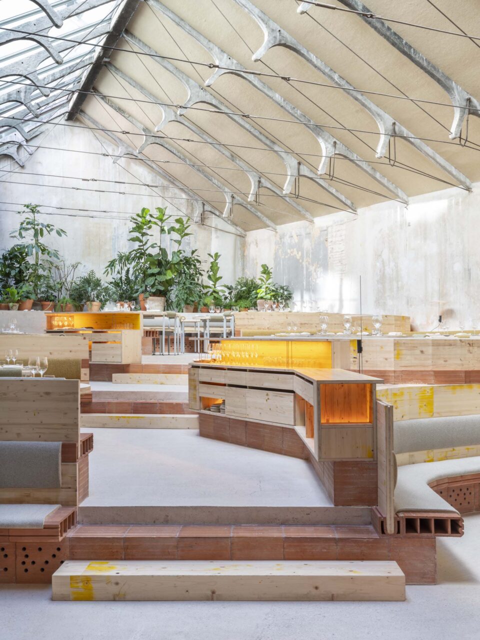 Restaurant benches are made with exposed clay blocks and wood under a gabled rood at TRAMO