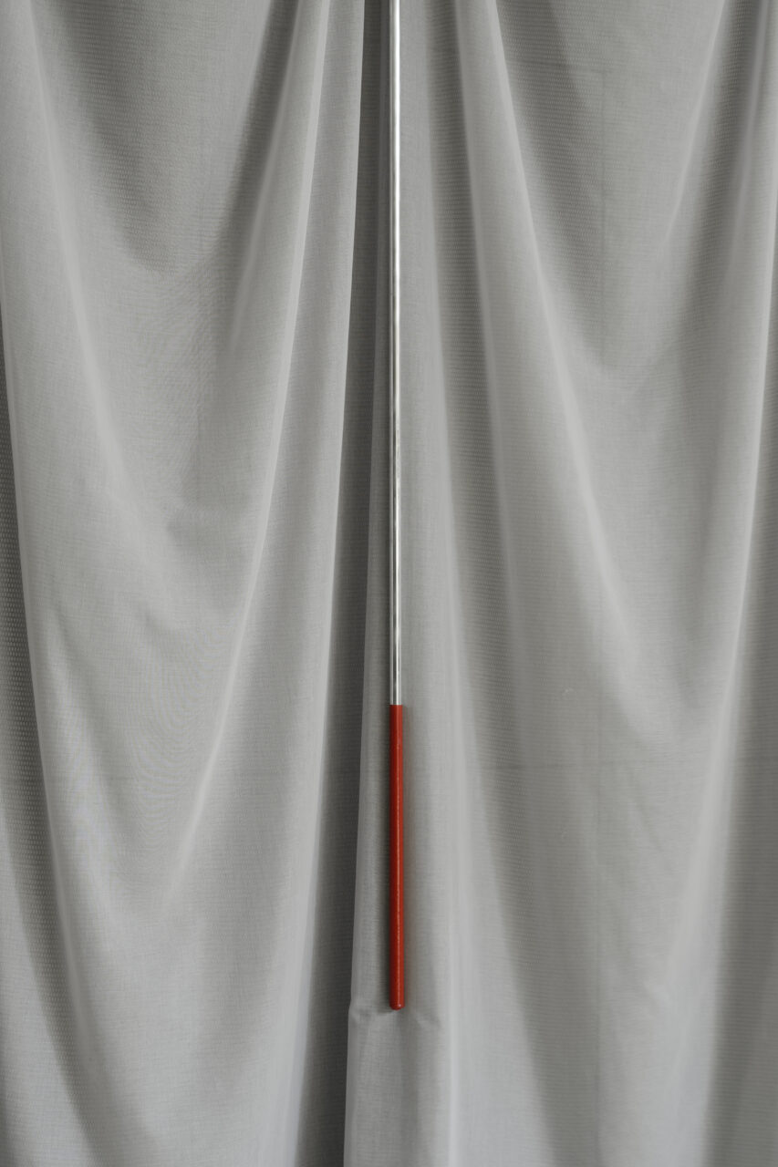 A handle with red accents sits in front of a gray, textured curtain at FOMU