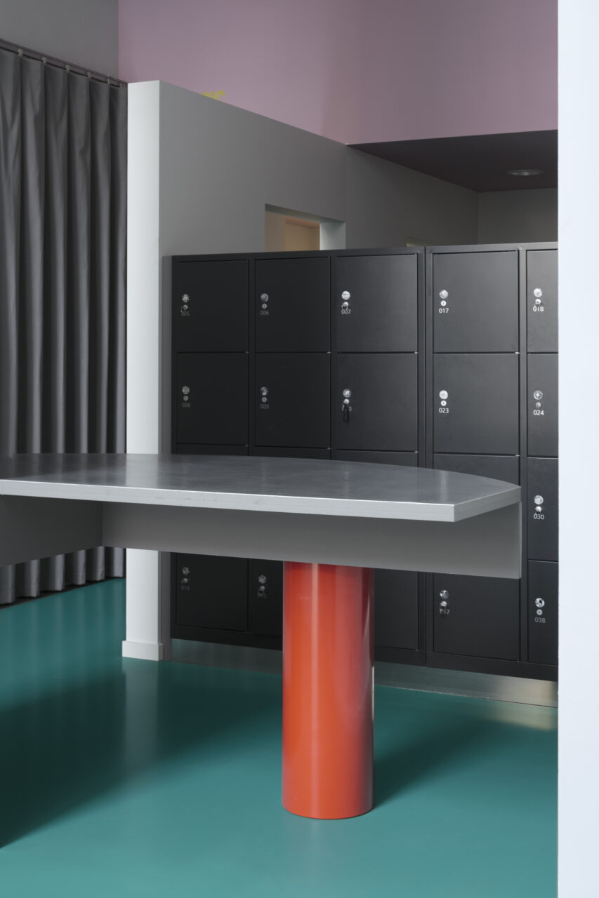 A curving table with a red leg sits in the new entrace of FOMU