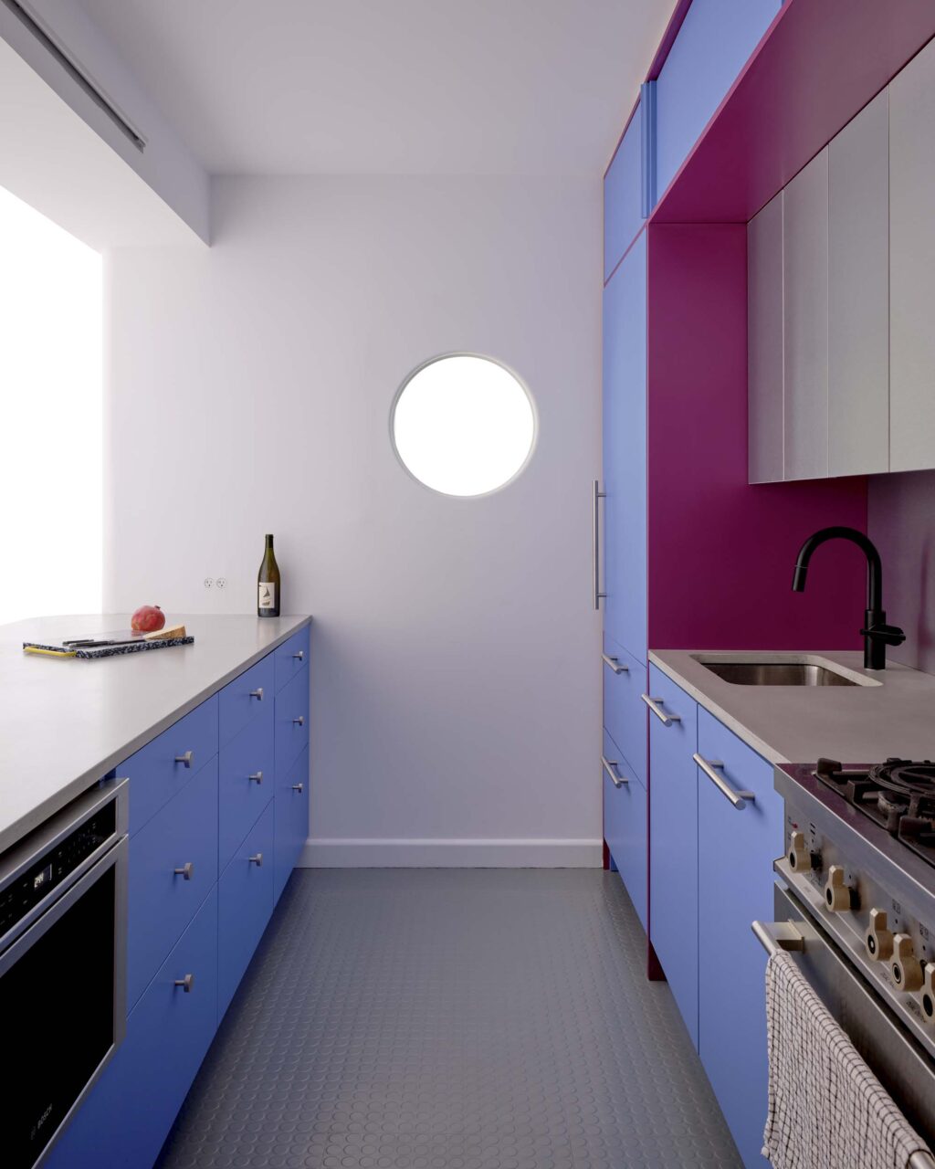 A porthole is on the wall of a kitchen by Ideas of Order