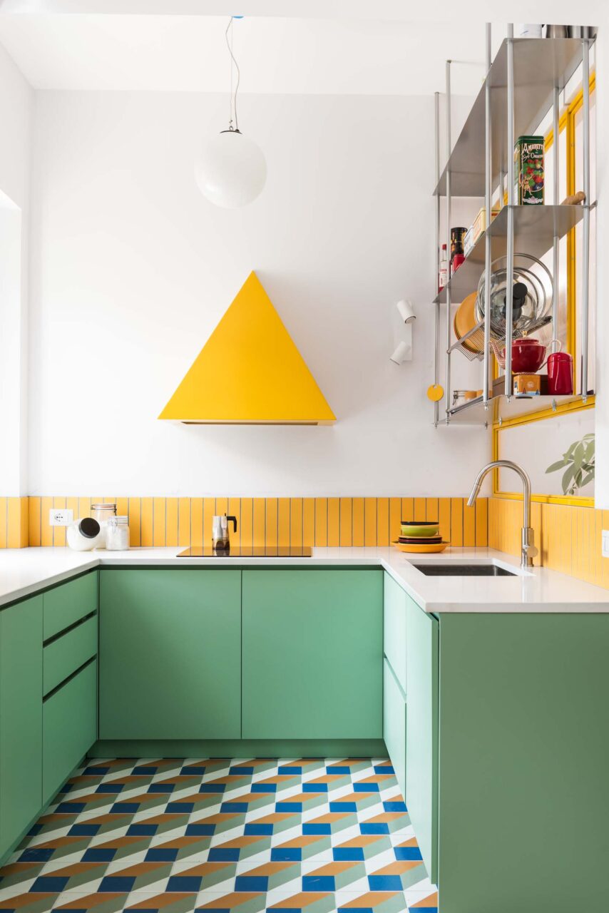 A yellow, triangular hood floats on the kitchen wall by 02A