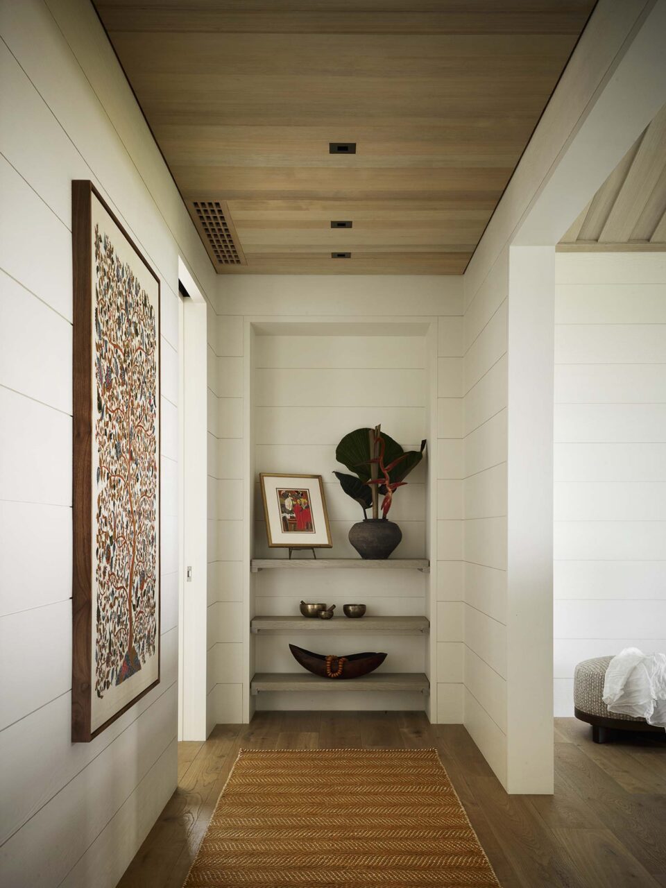 A hallway is clad in eggshell-painted walls and wooden floors and ceilings by Walker Warner