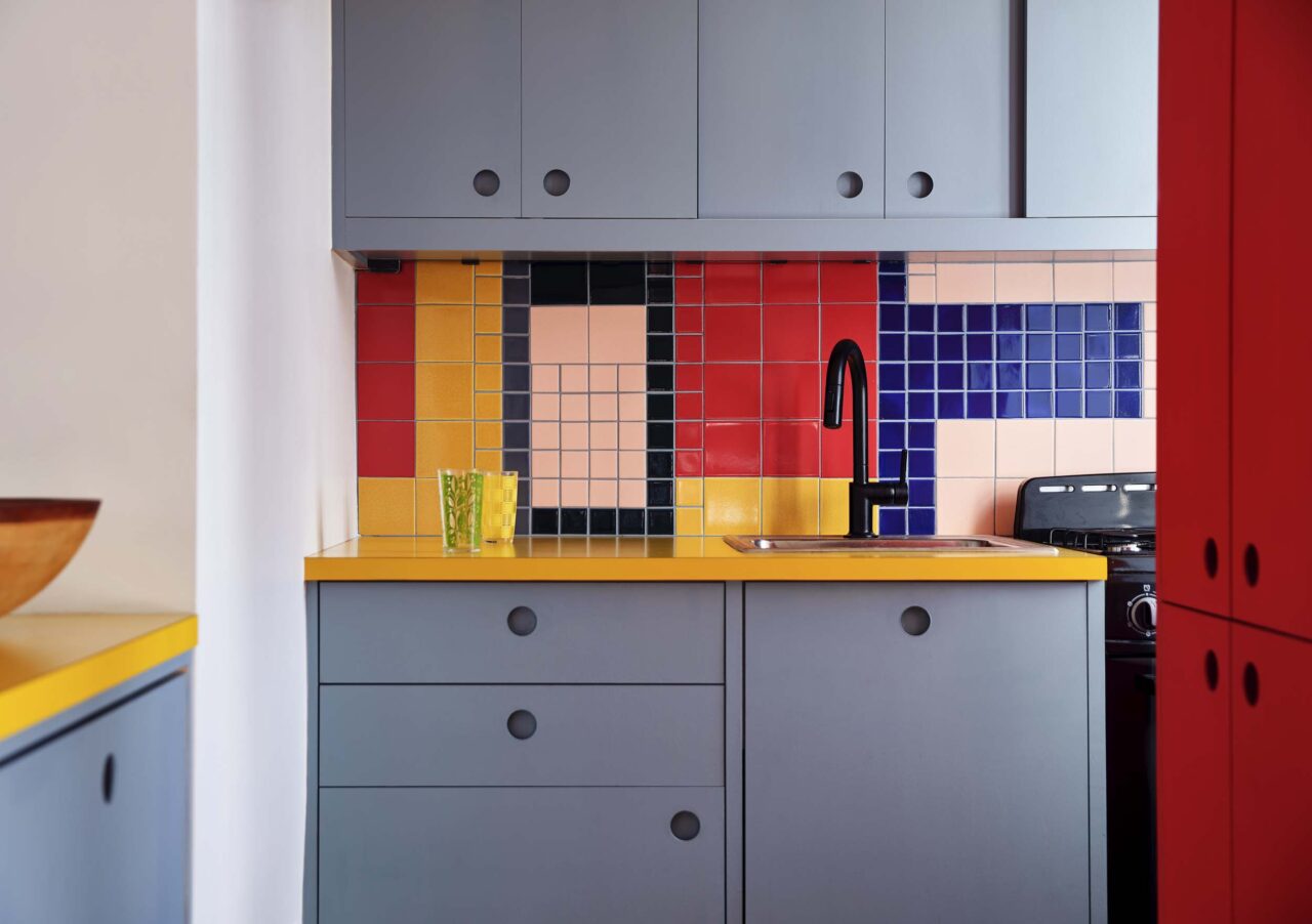 A colorful kitchen with contrasting hues in the backsplash by Sarah Jacoby