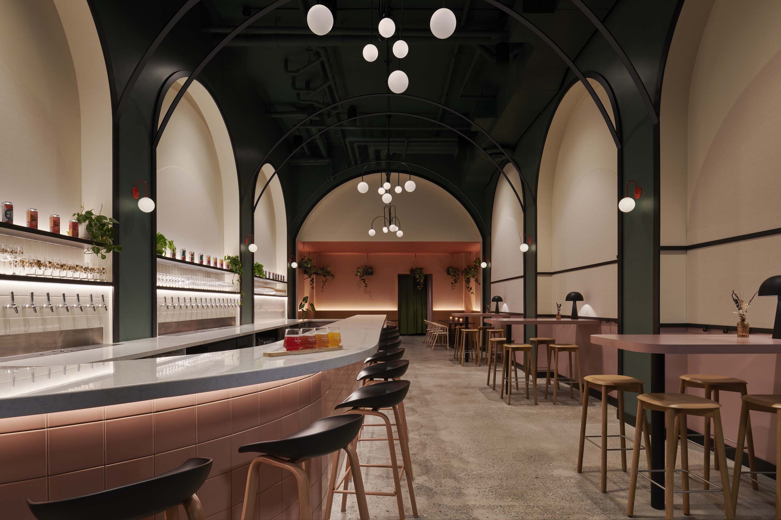 A taproom with dark green walls and metal archways from ALA Studio