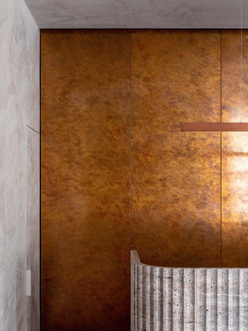 A patinated copper accent wall and fluted reception desk are part of Kallos Turin's design