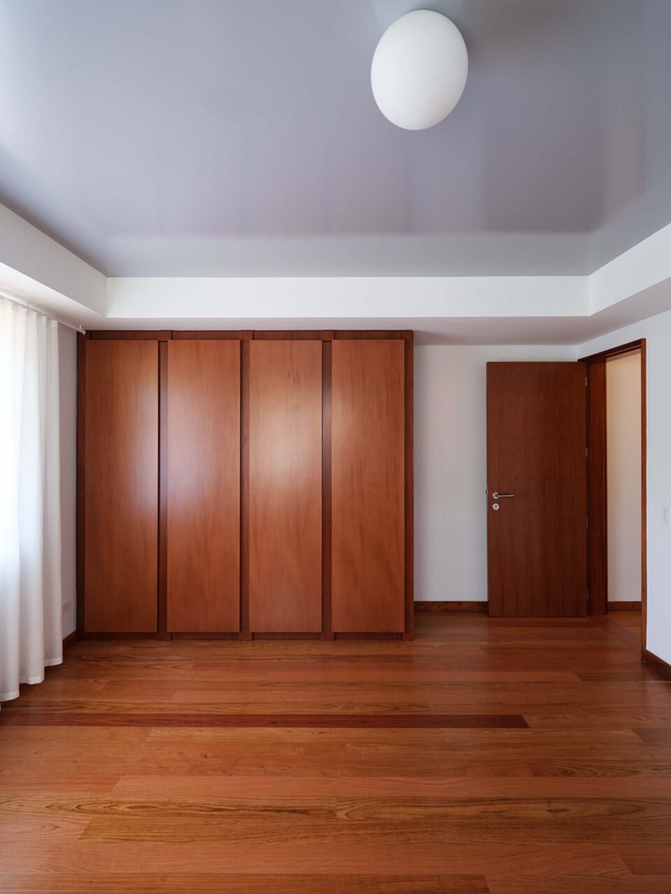 An empty bedroom with a wooden wardrobe and glossy ceiling at the Swiss embassy