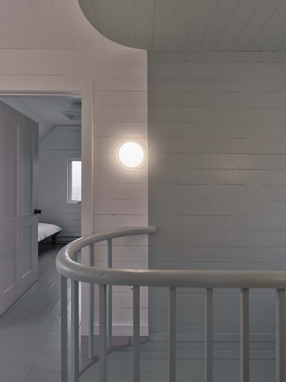 A curved stairway railing casts a shadow on the wall at Burdens Point