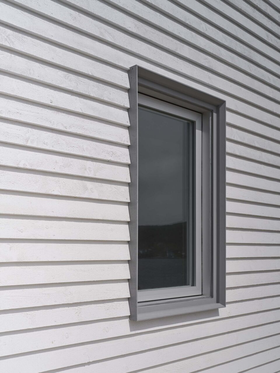 On a white shiplap-clad home, Burdens Point, a window has a projecting box