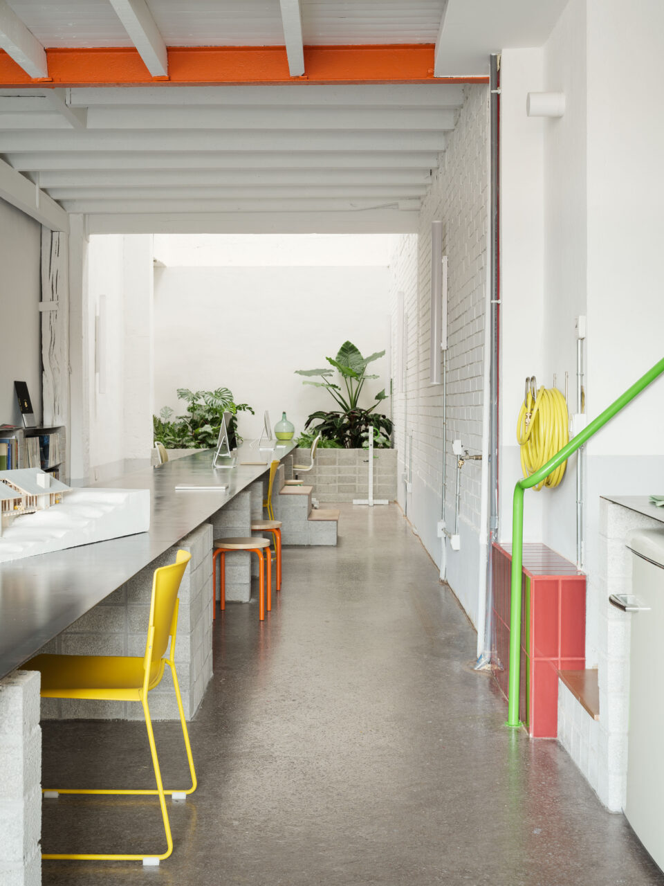A table runs down the space with colorful chairs going down the length