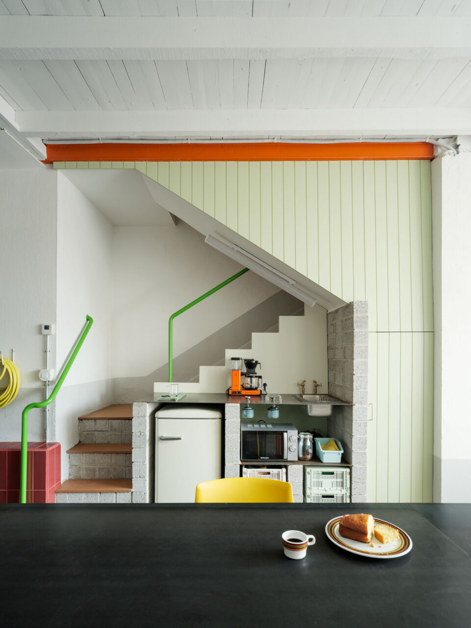 A small kitchen is tucked under the stairs designed by BeAr Architects