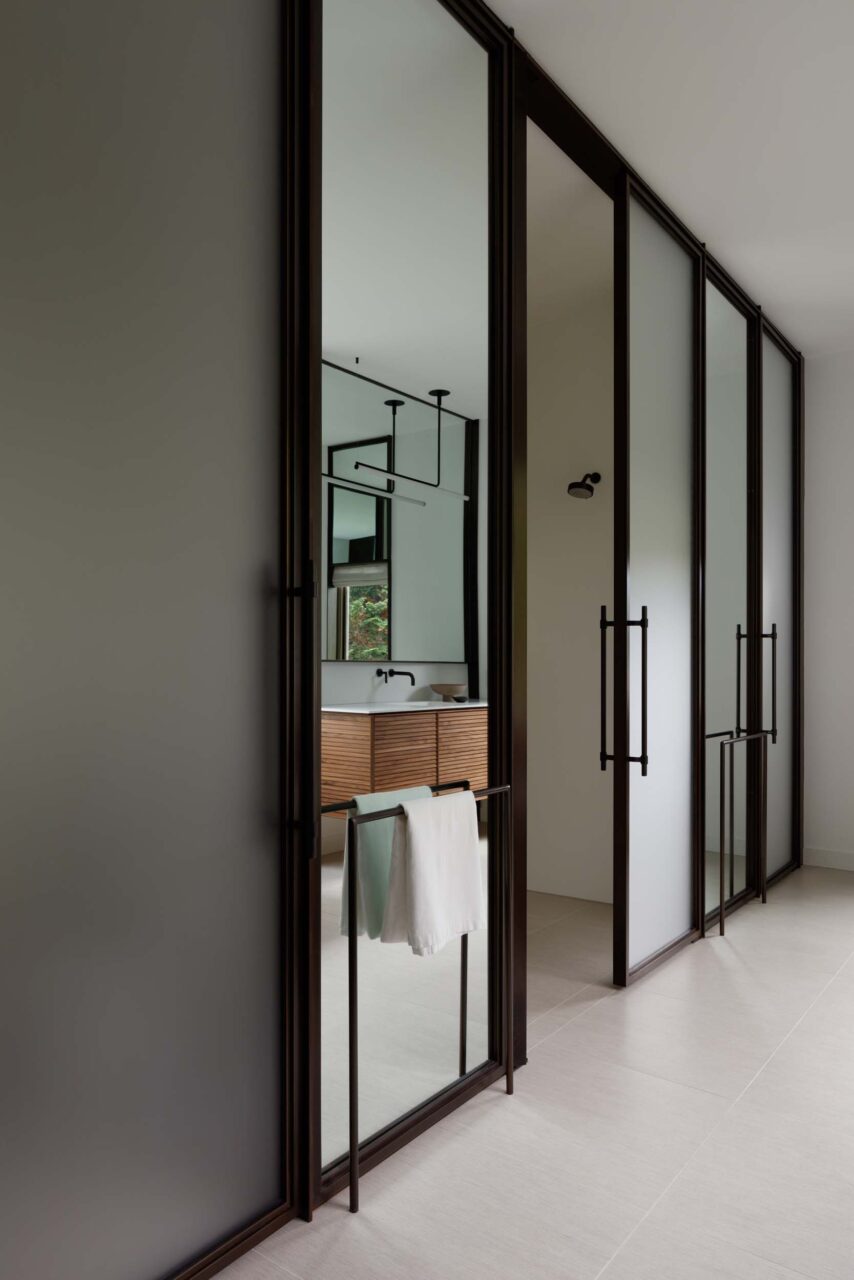 A wall of bronze panels of frosted glass and mirrors in a bathroom
