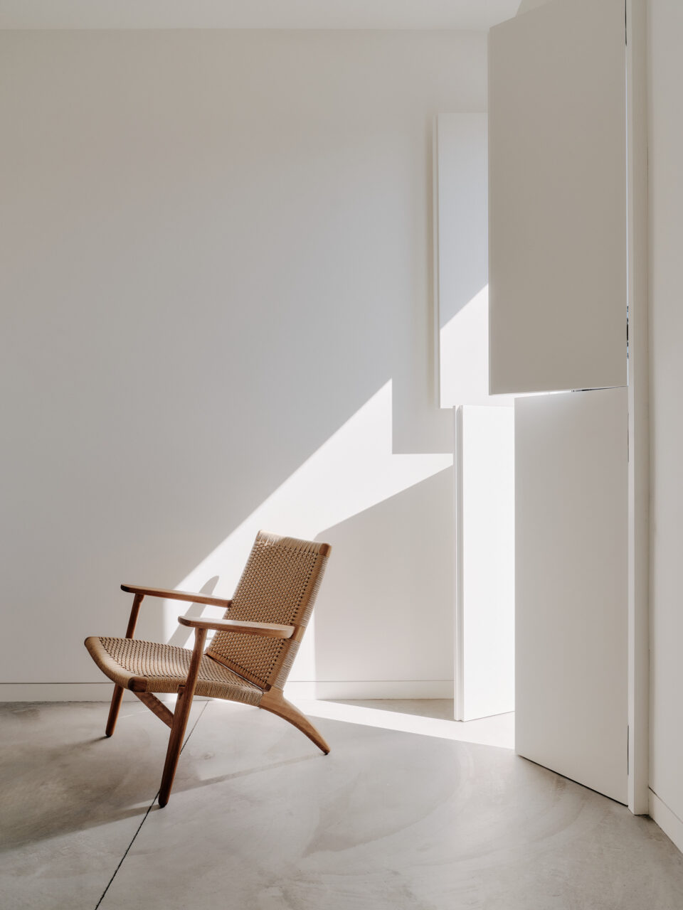 Light shines through paneled window coverings onto a chair