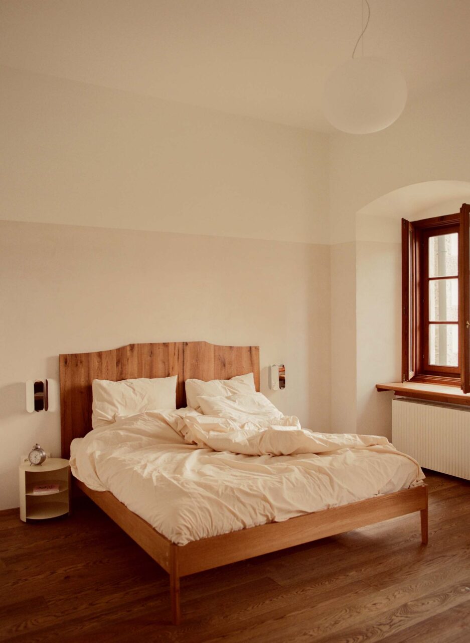 A bedroom in a renovated castle with a wooden headboard by Some Place Studio