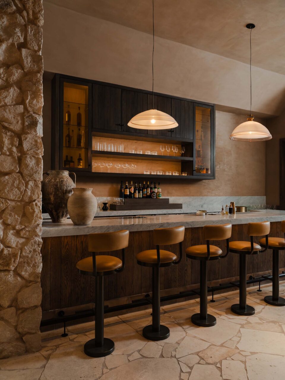 A bar by Sarah Carpenter & Studio clad in stone flooring and wall