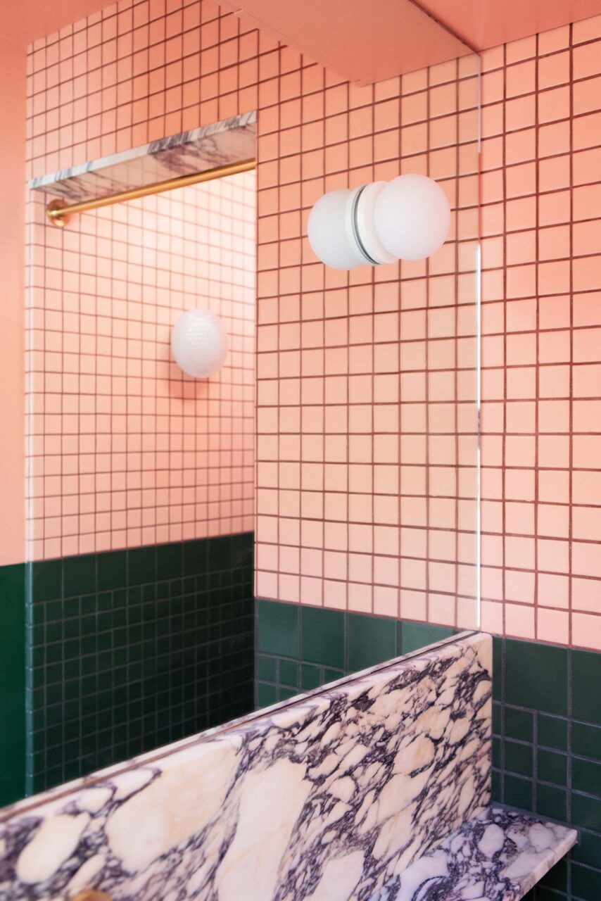 A pink and green tiled bathroom with marble backsplash