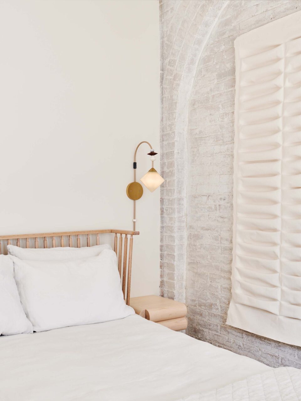 A bedroom with whitewashed exposed brick from Bernheimer