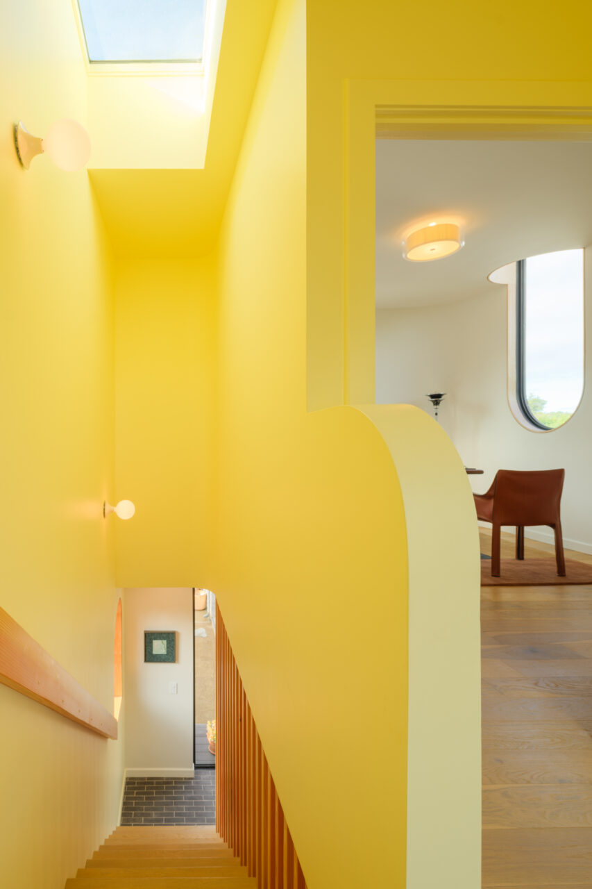 A yellow stairwell features a skylight on top in this ADU
