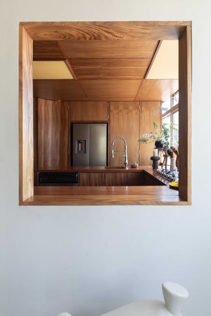 The wood-clad kitchen has a portal into the living room