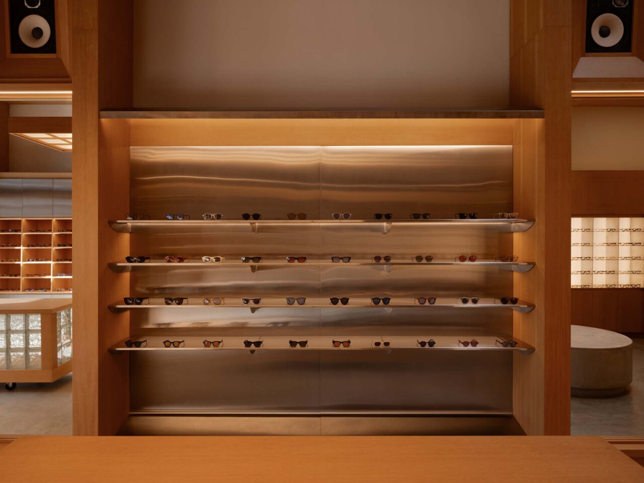 a wood shelf lined with eyeglasses inside Akila