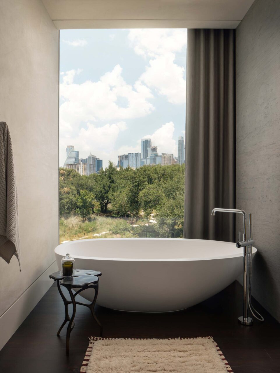 A bathroom tub in front of a large glass window