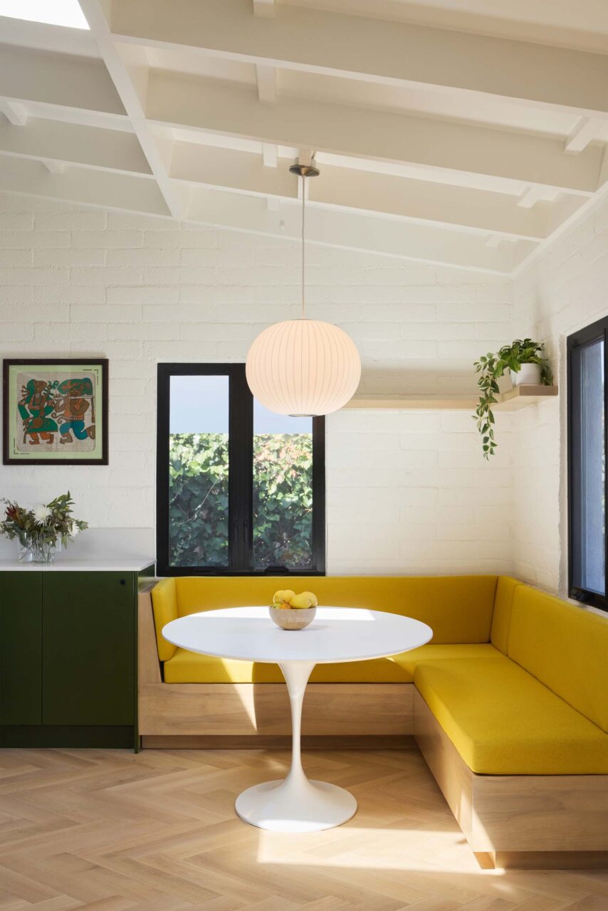 a yellow upholstered breakfast nook in kitchen in renovated house by shin shin