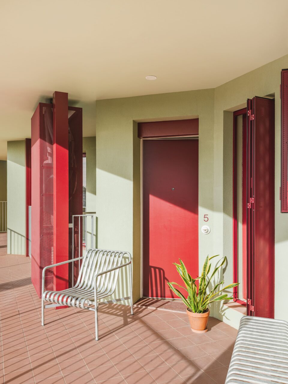 balcony with metal chair and red door
